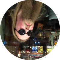 'An upside down photo of a bearded man wearing sunglasses at a pub'